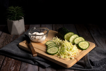 Sliced cabbage and cucumber lie on the table in the kitchen 