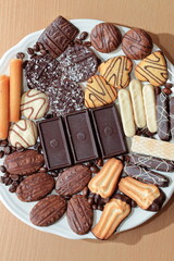 Close up of delicious bisquits and chocolate. Bisquits on plate top view, cookies on wooden empty space wood background. Macro sweets