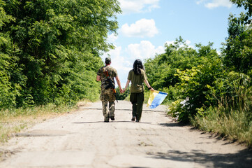 Fototapeta premium Ukrainian military defender with his wife, portrait of a young couple where the husband is a military man.