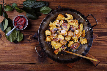 Traditioneller österreichisch Kaiserschmarren mit Zwetschgen und Rosinen serviert als close-up in einer rustikalen schmiedeeisernen Bratpfanne 
