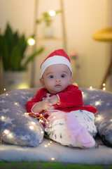 baby in santa hat sitting and posing on a pillow