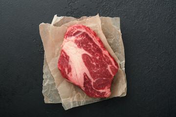 Raw beef steak. Raw fresh Chuck roll steak with rosemary, salt and pepper on cutting board on dark...