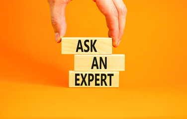Ask an expert symbol. Concept words Ask an expert on wooden blocks on a beautiful orange table orange background. Businessman hand. Business and ask an expert concept. Copy space. - obrazy, fototapety, plakaty