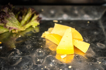 Pieces of the triangle cut cheese on the metal plate which is prepared for service in buffet meal. Food object photo, close-up and selective focus.