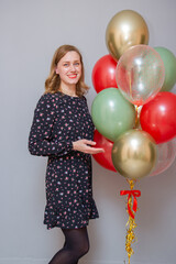 Fototapeta premium girl with red lipstick with a bunch of balloons against a gray wall