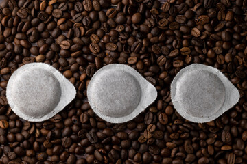 Paper pods for coffee machine on coffee beans background