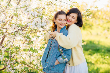 two attractive women hugging in a spring garden. 