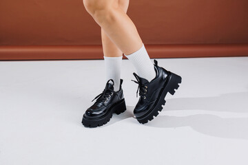 Beautiful female legs in leather black lace-up oxford shoes. Female legs with fashionable shoes and...