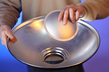 disassembly of a spotlight in a beauty dish by a person