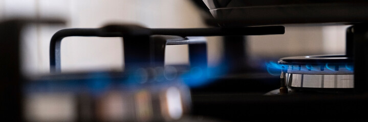 Burning gas burner with blue flames on kitchen black gas stove with a bokeh effect. gasoline. Banner