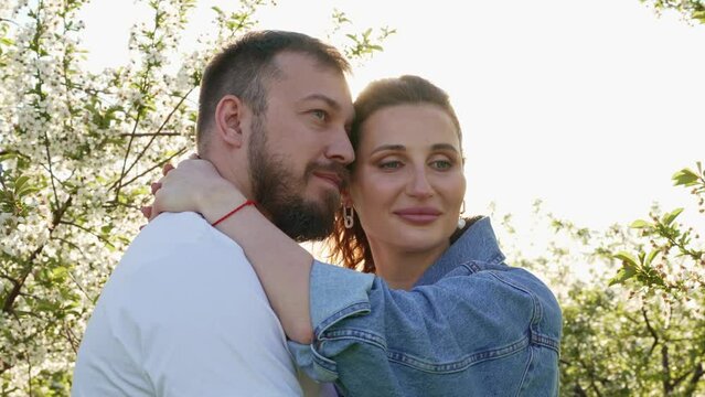a lovers man and a woman in a blooming spring garden. sunlight.