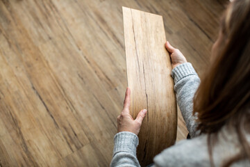 Woman choosing laminate floor design from samples in flooring store