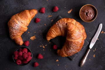 Delicious sweet croissant with fresh fruit and chocolate on dark background