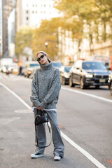 Naklejka premium full length of stylish woman in sunglasses and grey outfit holding black handbag on street of New York city