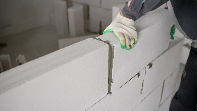 A construction site on which the walls are built of aerated concrete bricks. Empty walls of new buildings from the gas block. Installation of a wall of white blocks in a new apartment.