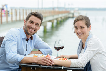 portrait of couple having a meal on a waterside terrace
