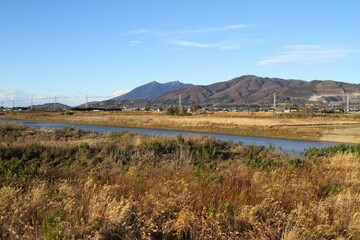 Beautiful Japanese Rural Landscape with a River running in front of a Mountains on a Clear Winter Afternoon