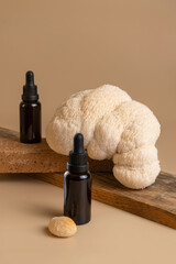 Two Bottles of dark amber glass with essential oil with beautiful lion mane mushroom on beige...