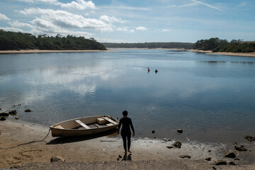 Fototapeta na wymiar Mergulhadora com o seu fato de mergulho a caminhar para a água junto a um barco no País basco, França