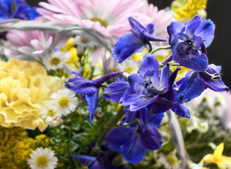 Purple flowers in a bouquet with pink, purple, yellow and white flowers in a basket.
