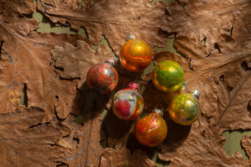 Winter mood- toys for decorating the Christmas tree on a background of oak leaves