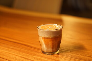 Inside a cafe with windows. Black sesame latte placed on a wooden table.