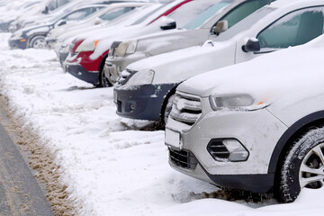 Cars covered in snow parked in row on parking lot in winter seson, top view. Parked cars covered with snow after snow storm.