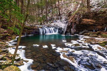 Winter forest stream mountain scene with a waterfall flowing over rocks and boulders on the Little...