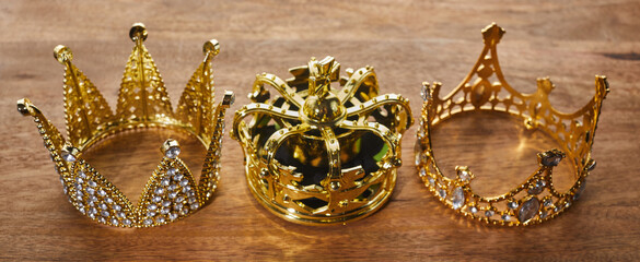 Happy Epiphany day. Three gold crowns on wooden background, symbol of Tres Reyes Magos, Three Wise...