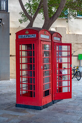 Obraz premium Gibraltar cityscape. Close up of two empty typical English red telephone boxes on pedestrian main street at centre of Gibraltar. UK