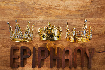 Happy Epiphany day. Three gold crowns on wooden background, symbol of Tres Reyes Magos, Three Wise...