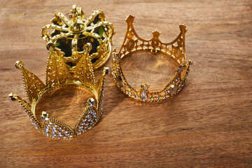 Happy Epiphany day. Three gold crowns on wooden background, symbol of Tres Reyes Magos, Three Wise Men. 