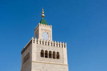 Close-up Ez-Zitouna Mosque minaret against a blue sky in the old city of Tunis. Famous Islamic landmark in Tunisia.