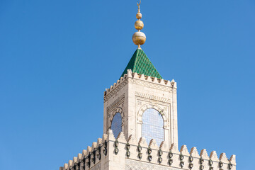 Close-up Ez-Zitouna Mosque minaret against a blue sky in the old city of Tunis. Famous Islamic landmark in Tunisia.