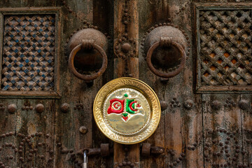 Algeria and Tunisia flag on a copper plate hanging on an old wooden door in the market in Tunis, Tunisia.