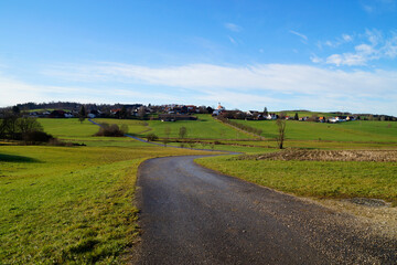 Fototapeta na wymiar an endless road leading through the scenic Bavarian countryside Konradshofen on a sunny December day with blue sky just before Christmas (Germany) 