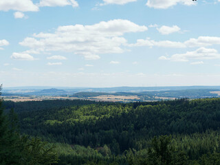 Obraz premium Landschaft in Hessen. Waldgut von Burgwald entlang Gerlachsberg und Stirnhelle-Rundweg. Blick uber den Hoherodskopf auf die Amöneburg, Lahnberge, Schloss Marburg und Windpark Marburg 