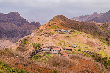 Stone houses and a footpath on a mountain range with bushes and grass on Santiago Island, Cabo Verde
