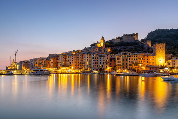 Fototapeta na wymiar Die mittelalterliche Hafenstadt Portovenere mit bunten Hausfassaden im Abendlicht bei spiegelnden Lichtern im Meer