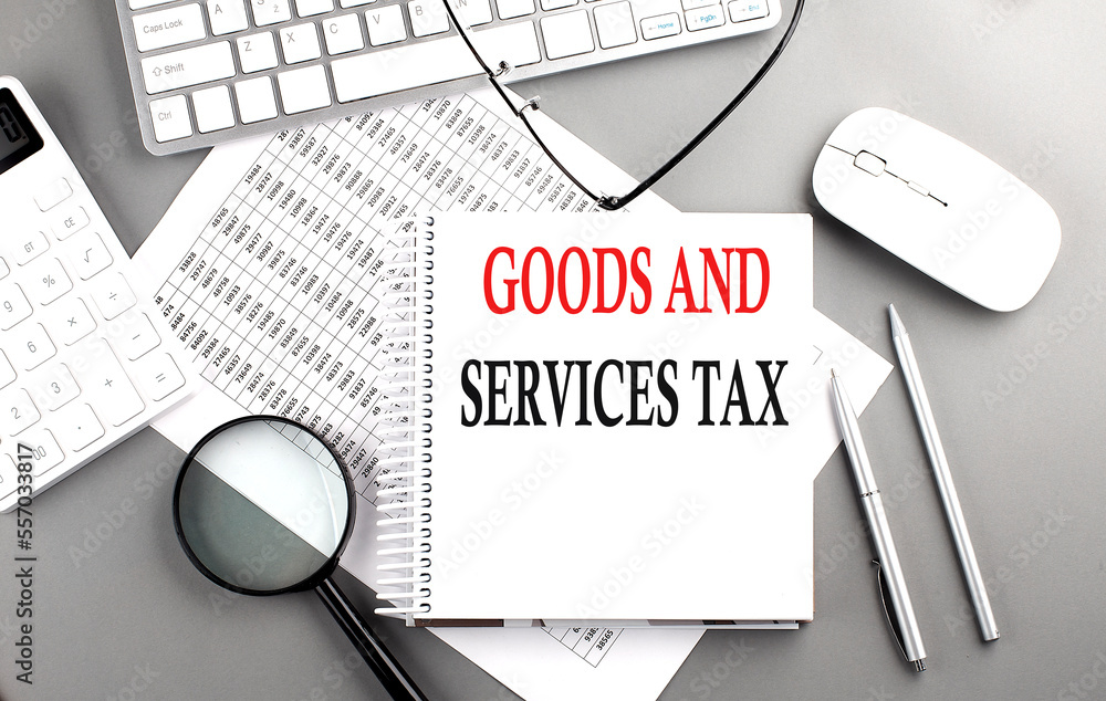 Poster goods and services tax text on notepad on chart with keyboard and calculator on grey background