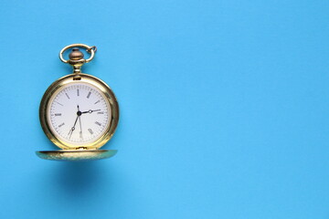 Golden pocket watch on a blue background.