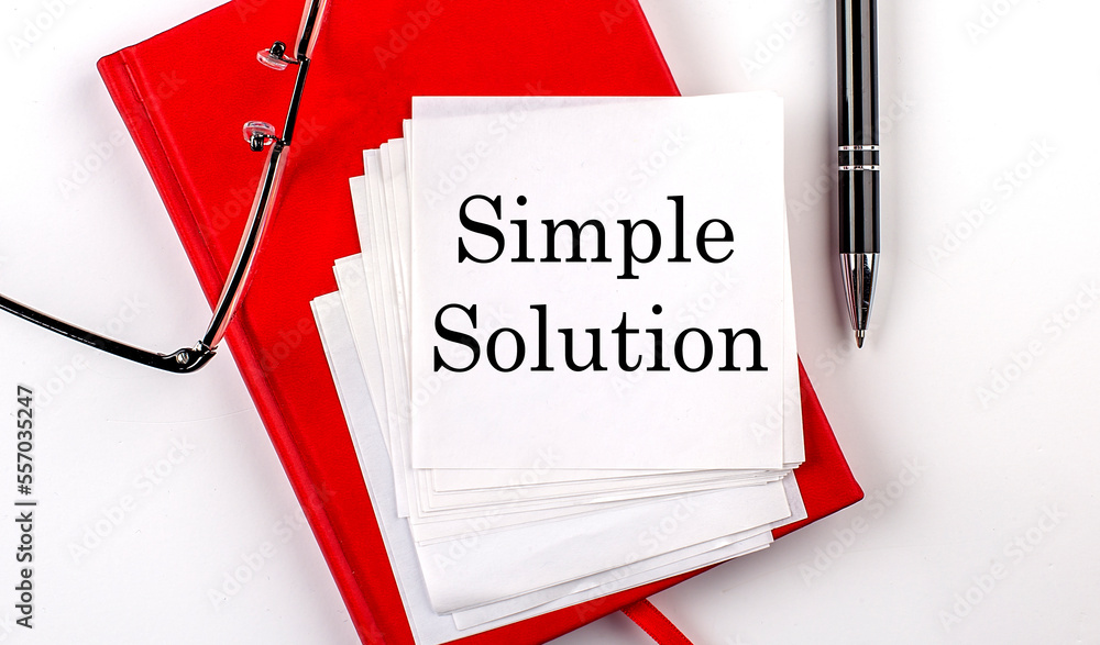 Aufkleber simple solution text on sticker on red notebook with pen and glasses