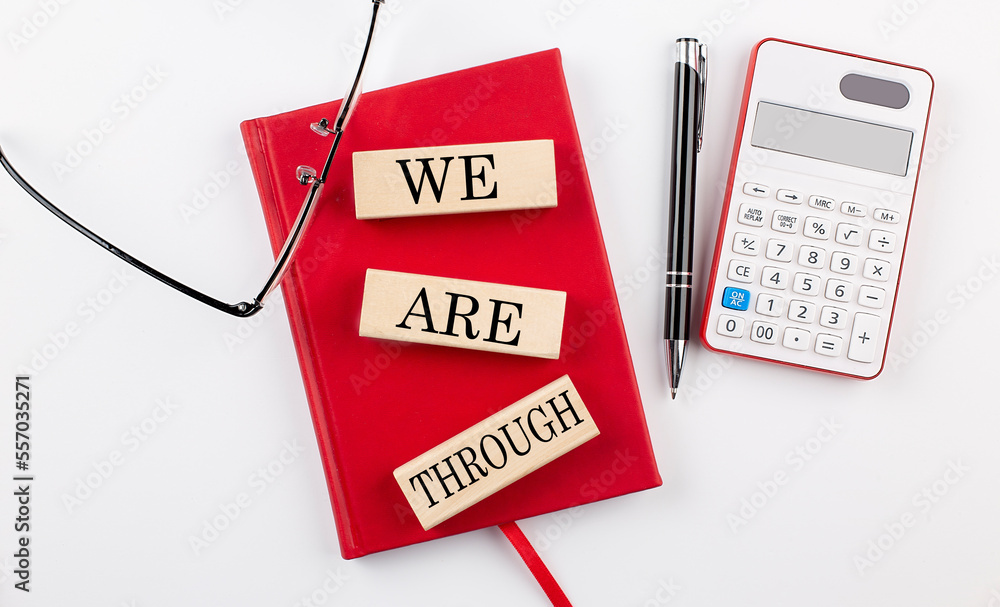 Poster we are through text on wooden block on red notebook