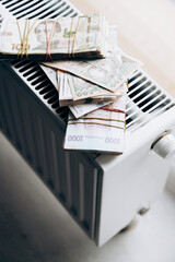 Three bundles of Ukrainian hryvnia money lie in a pile on the battery. Heating season. Currency of Ukraine. monetary system