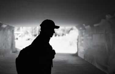 Silhouette of man walking alone in the city caring backpack 