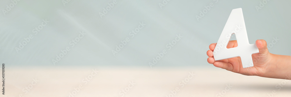Aufkleber number four in hand. hand holding white number 4 on blurred background with copy space. concept with