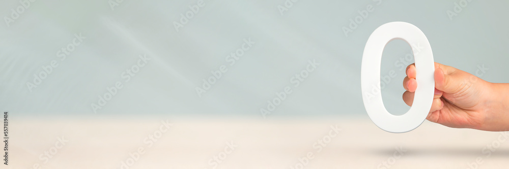 Aufkleber Numeral zero in hand. A hand holds a white number zero on a blurred background with copy space. Zero concept, 0 percent interest rate, minimum air emissions, cost or credit no increase.