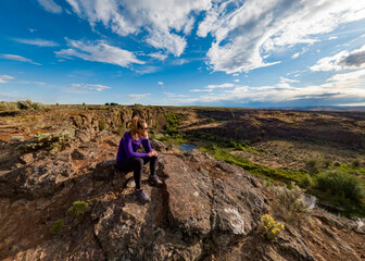 Athletic adventurous female hiker sitting on a ridge, overlooking a beautiful valley in Eastern Washington along the Columbia River.