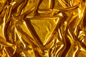 Golden wavy abstract background from a luxurious fabric, wavy folds, in the center a place for your gift in the form of a triangle