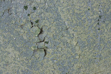 Peeling paint on the wall. Old concrete wall with cracked flaking paint. Weathered rough painted surface with patterns of cracks and peeling. Grunge texture for background and design. High resolution.